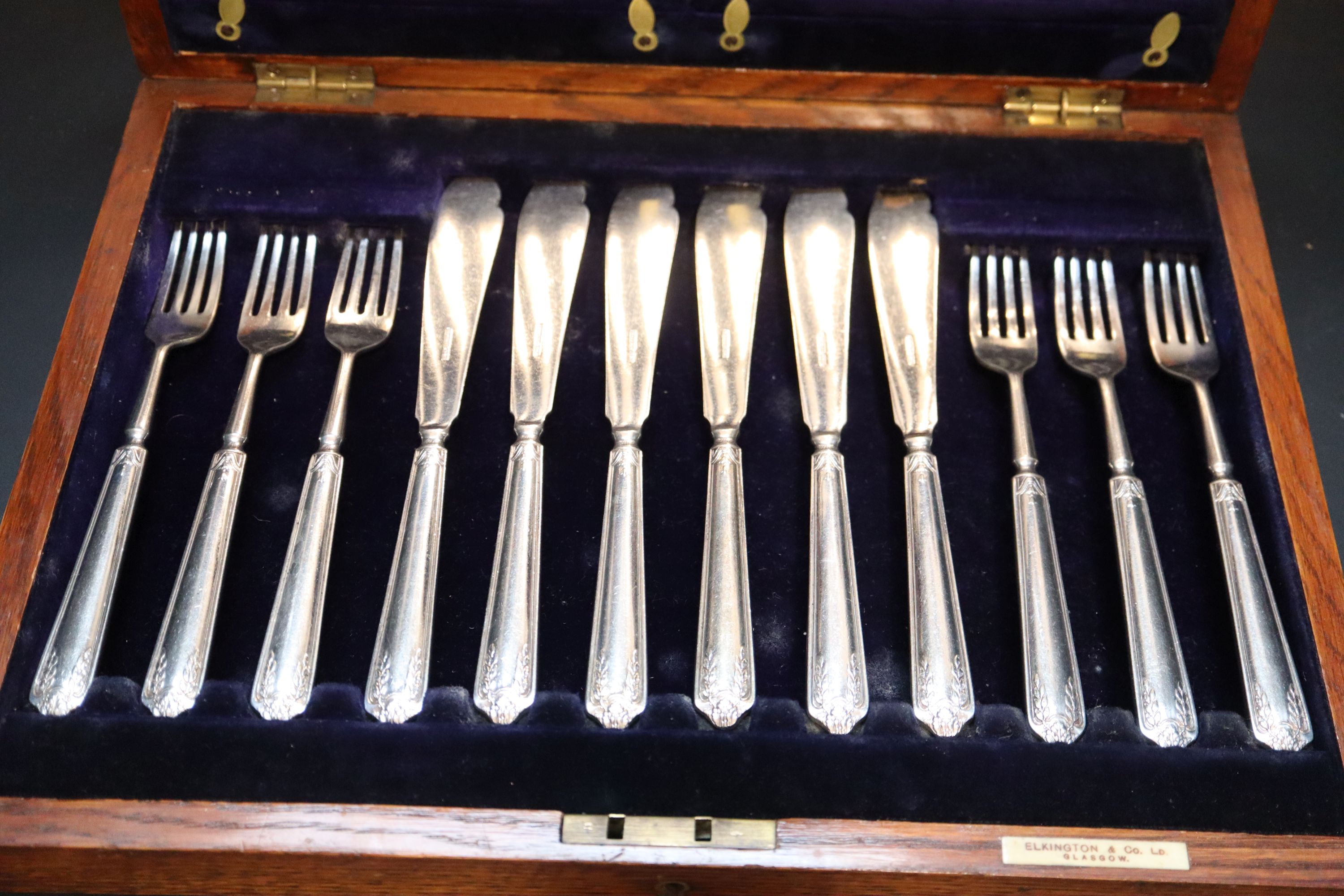 An oak cased set of twelve pairs of Elkington & Co silver plated fish knives and forks,